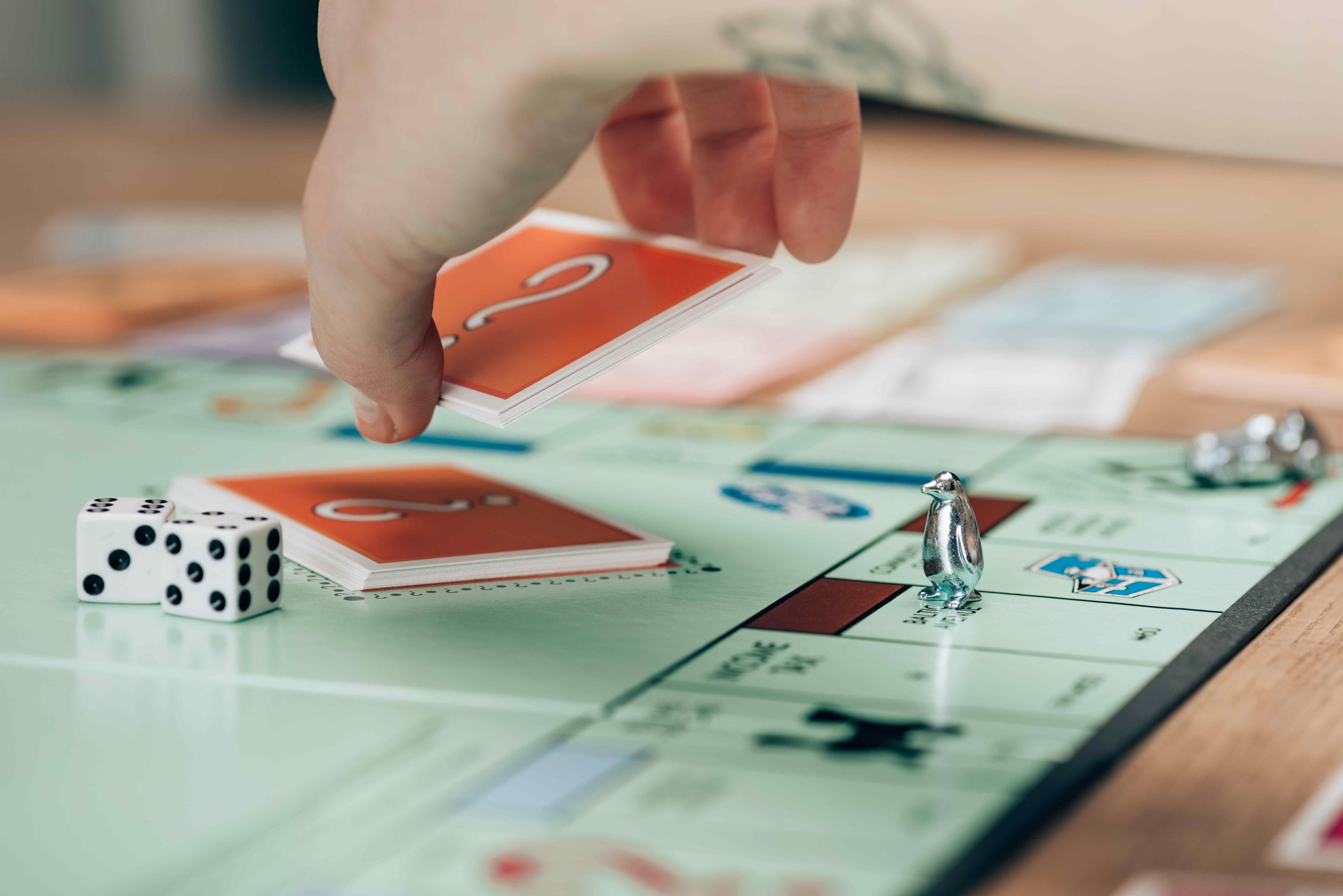 Woman's hand picking up cards from the middle of a Monopoly board game
