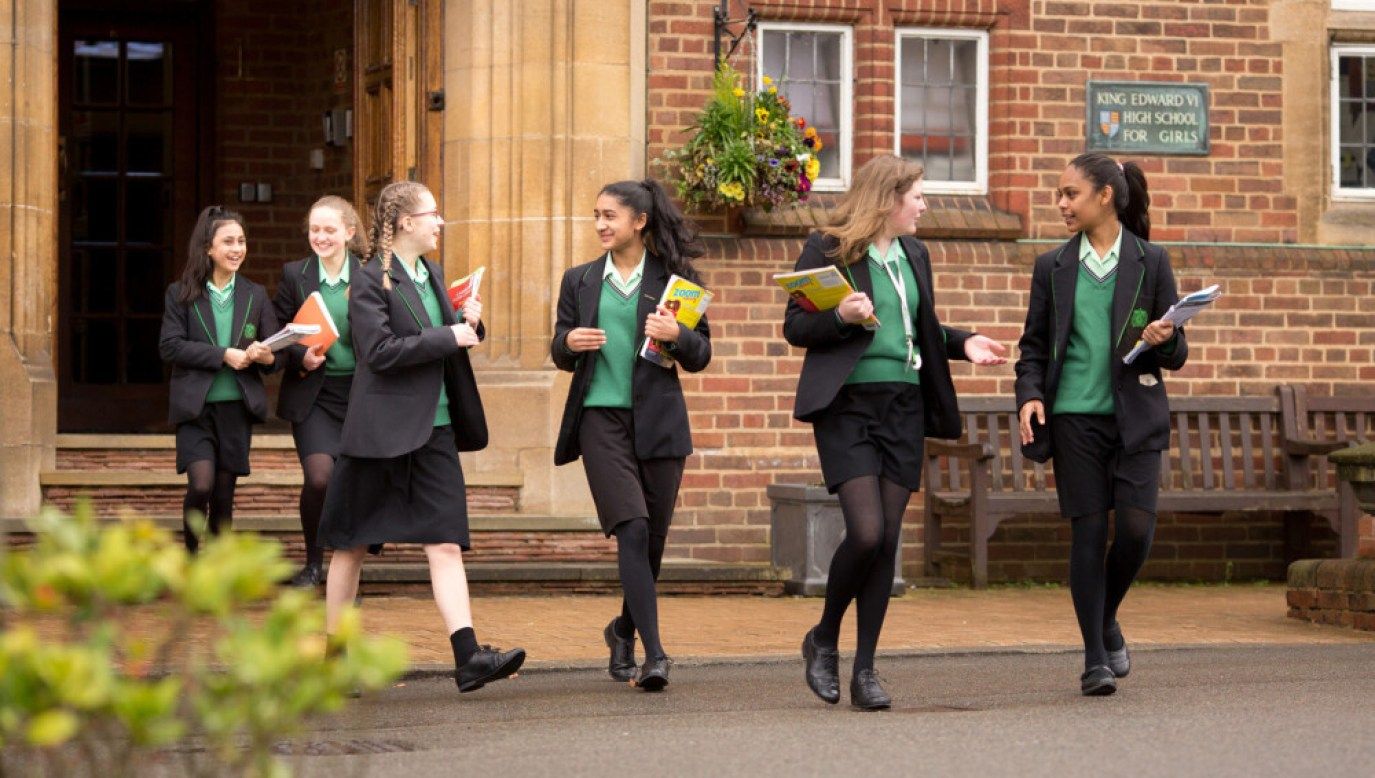 Students walking and talking outside the main entrance building at King Edward VI High School for Girls