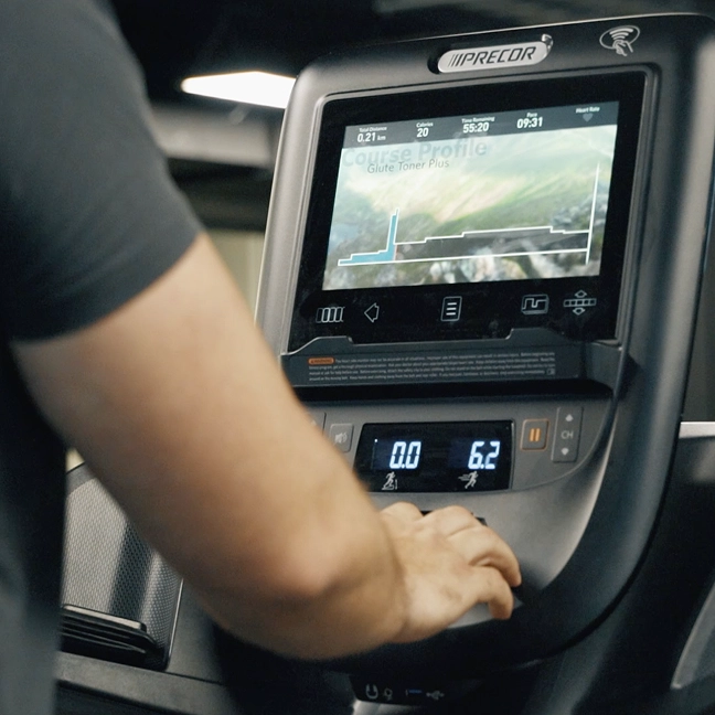 Gym member adjusting a Precor cardio machine during a training session