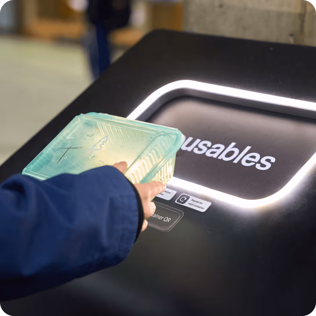 Image of someone returning a reusable container to a smart return bin at a hospital