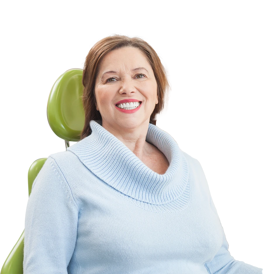 Smiling middle-aged woman wearing a light blue sweater sitting in a green chair.