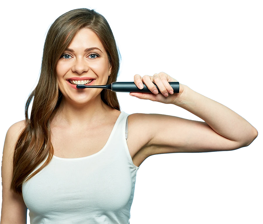Smiling woman in white tank top holding a black electric toothbrush near her mouth against a blue background.