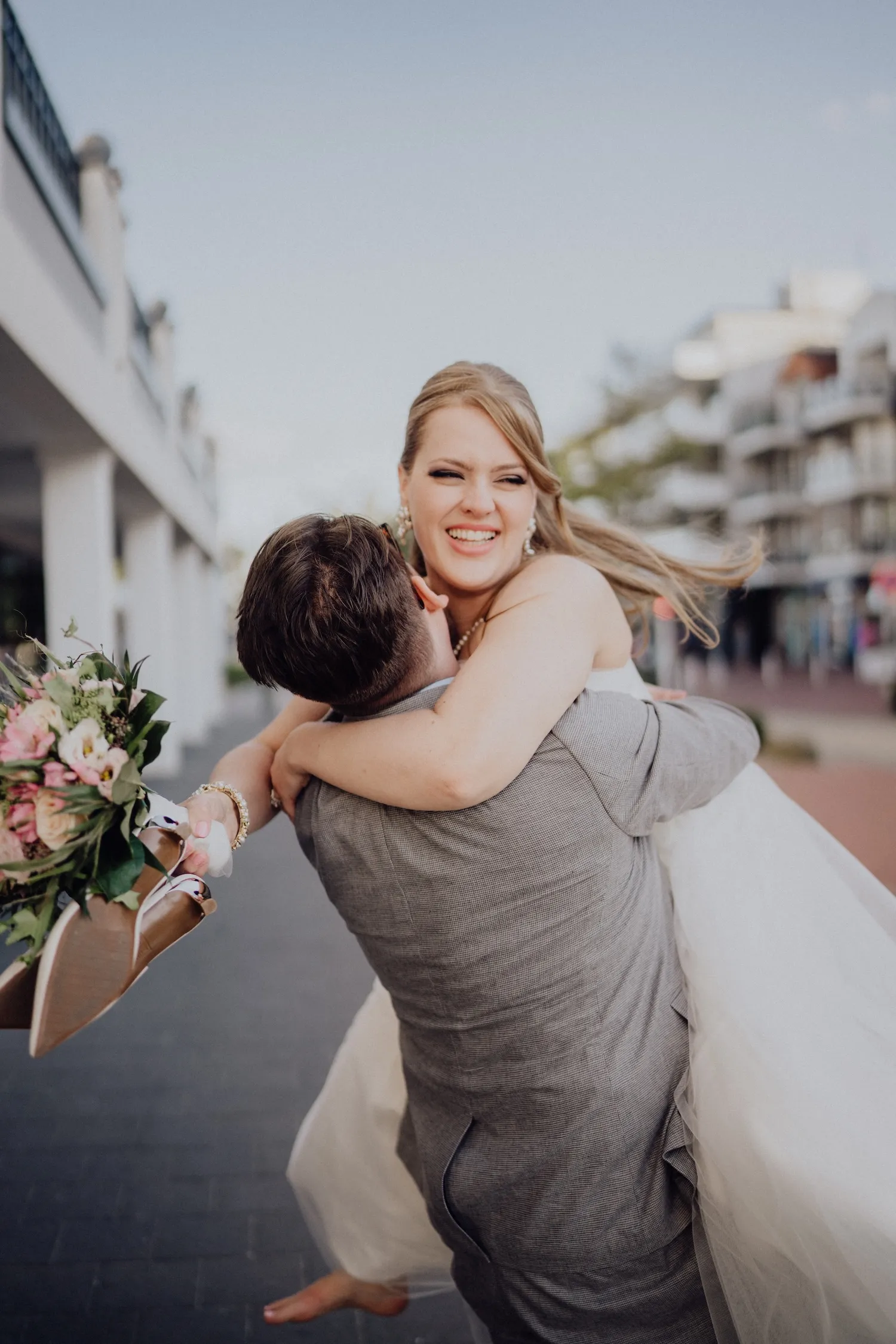 Braut und Bräutigam küssen sich bei einer Hochzeit, der Bräutigam trägt Anzug und Fliege, die Braut ein Spitzenhochzeitskleid mit Schleier.