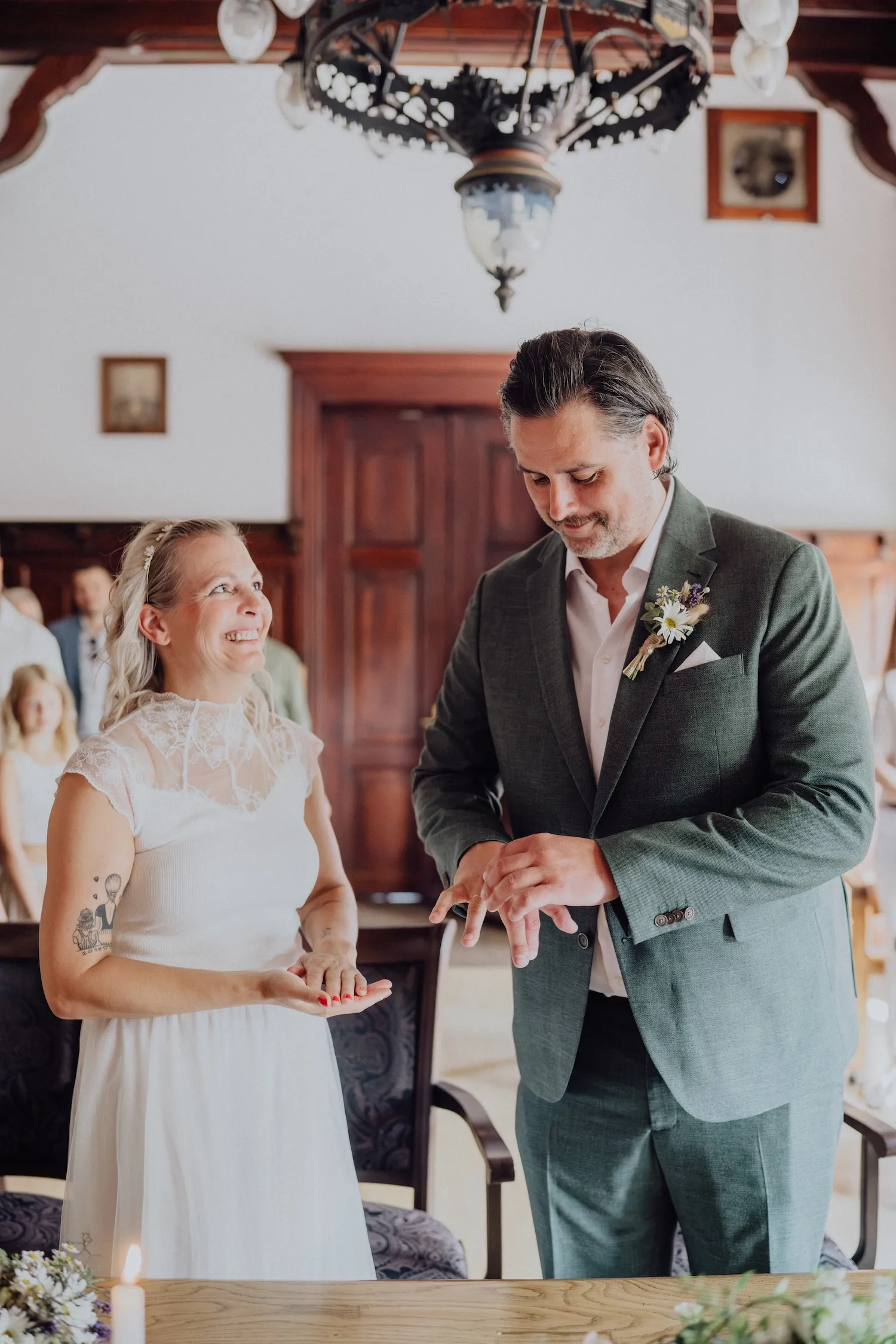 Vier Männer in Anzügen stoßen mit Bierflaschen bei einer Hochzeit an und lachen.