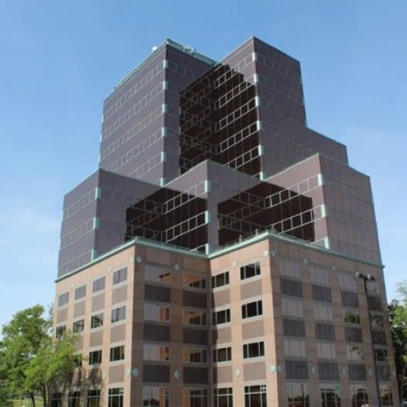 Modern multi-story office building with brown glass windows under clear blue sky.