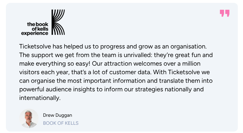 Two men shaking hands during a social interaction, one wearing a blue and green patterned scarf and glasses.