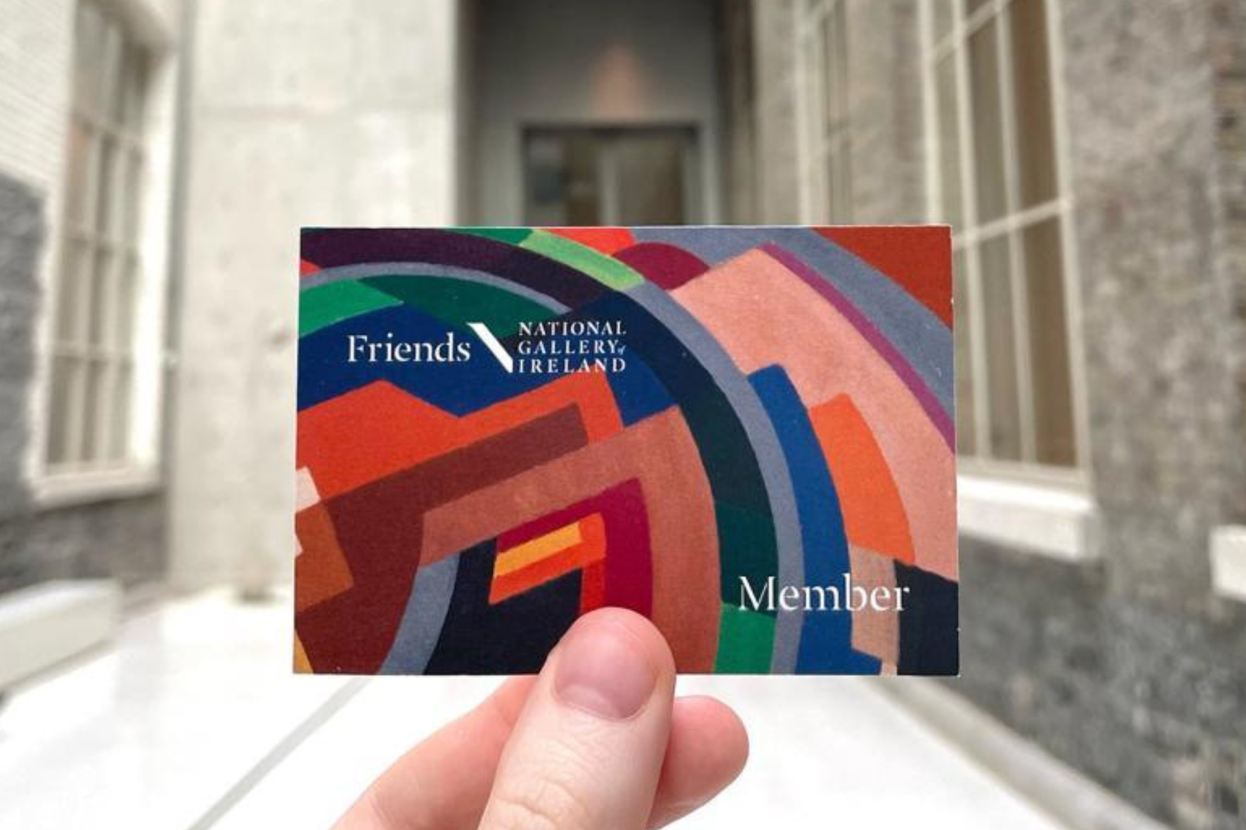 Four women casually chatting and smiling near a staircase at an indoor event.