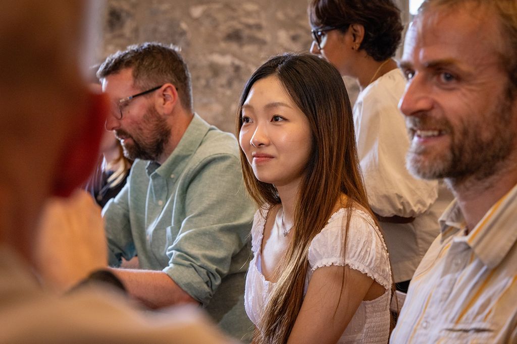 A group of five adults engaged in a conversation in a casual setting, all appearing attentive and expressive.