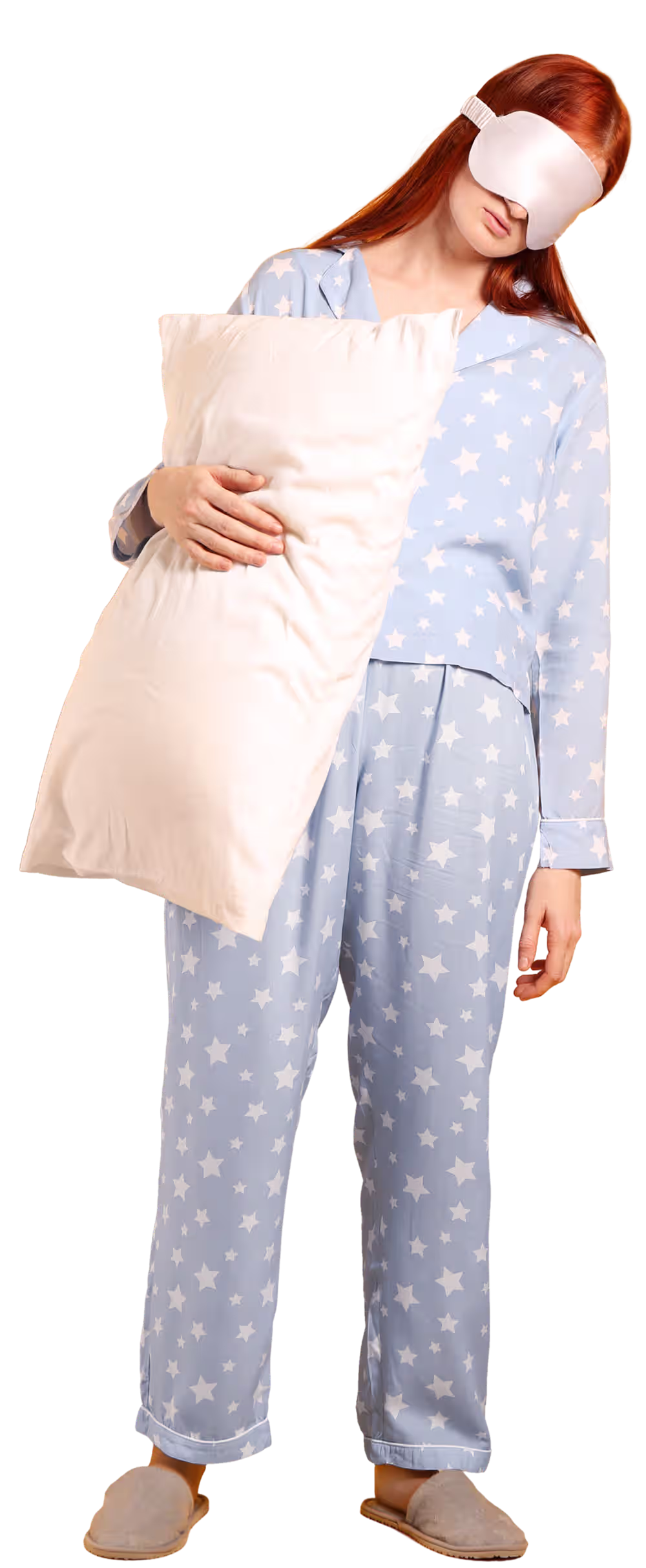 Mulher de pijama enquanto segura uma almofada e usa uma venda para dormir.