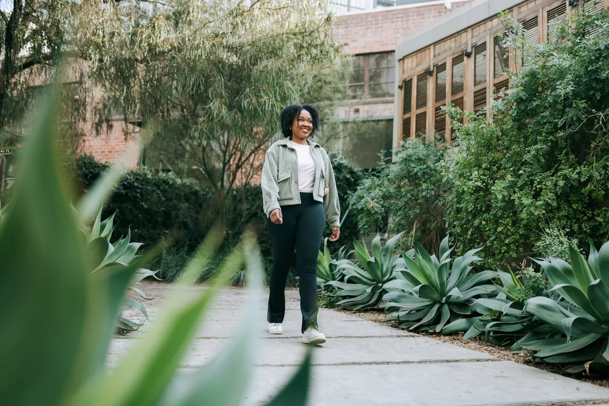 Young woman of colour walking on a path in a garden 