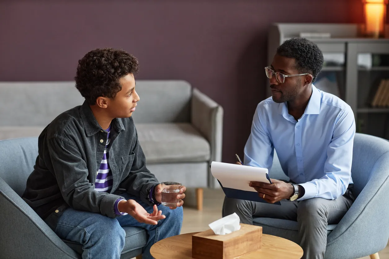 teenage boy, in a therapy session with a male therapist.