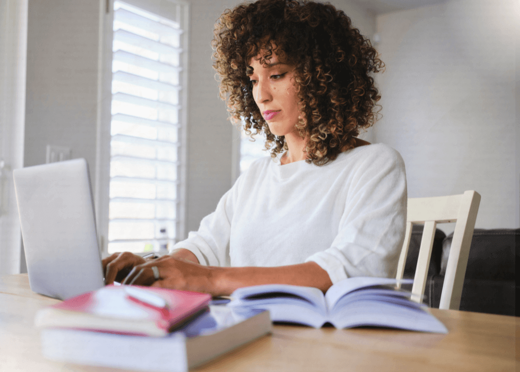 woman learning on her computer with books open around her