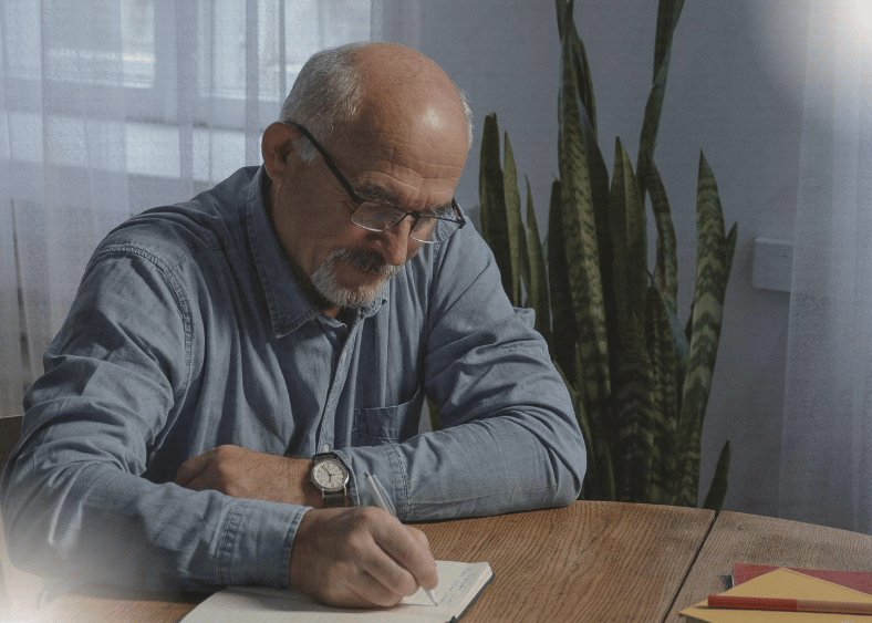 older man writing in a notebook 