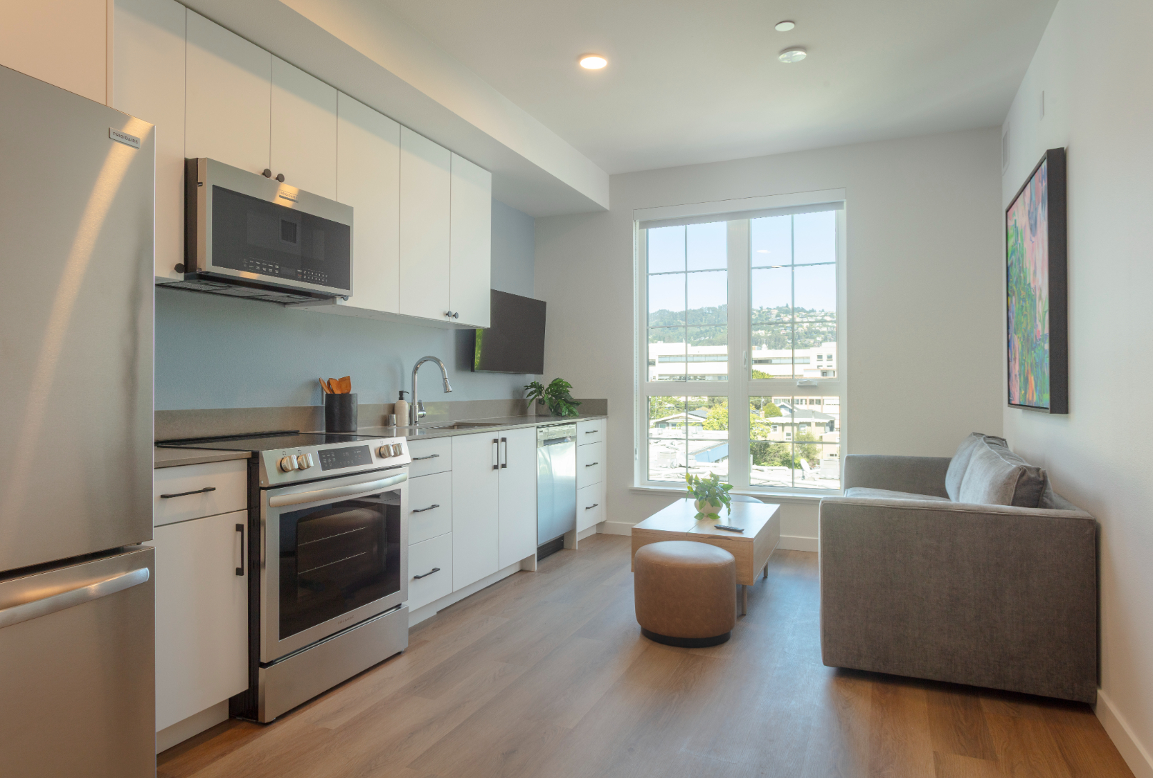 Close-up of the modern apartment kitchen featuring a stainless steel range/stove, dark countertops, and unique purple base cabinets at ArtHaus Telegraph in Berkeley, CA.