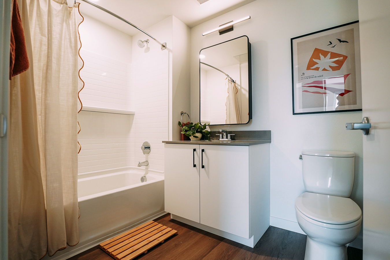 Apartment bathroom featuring a vanity, a framed mirror, and a white shower/tub with shower curtain