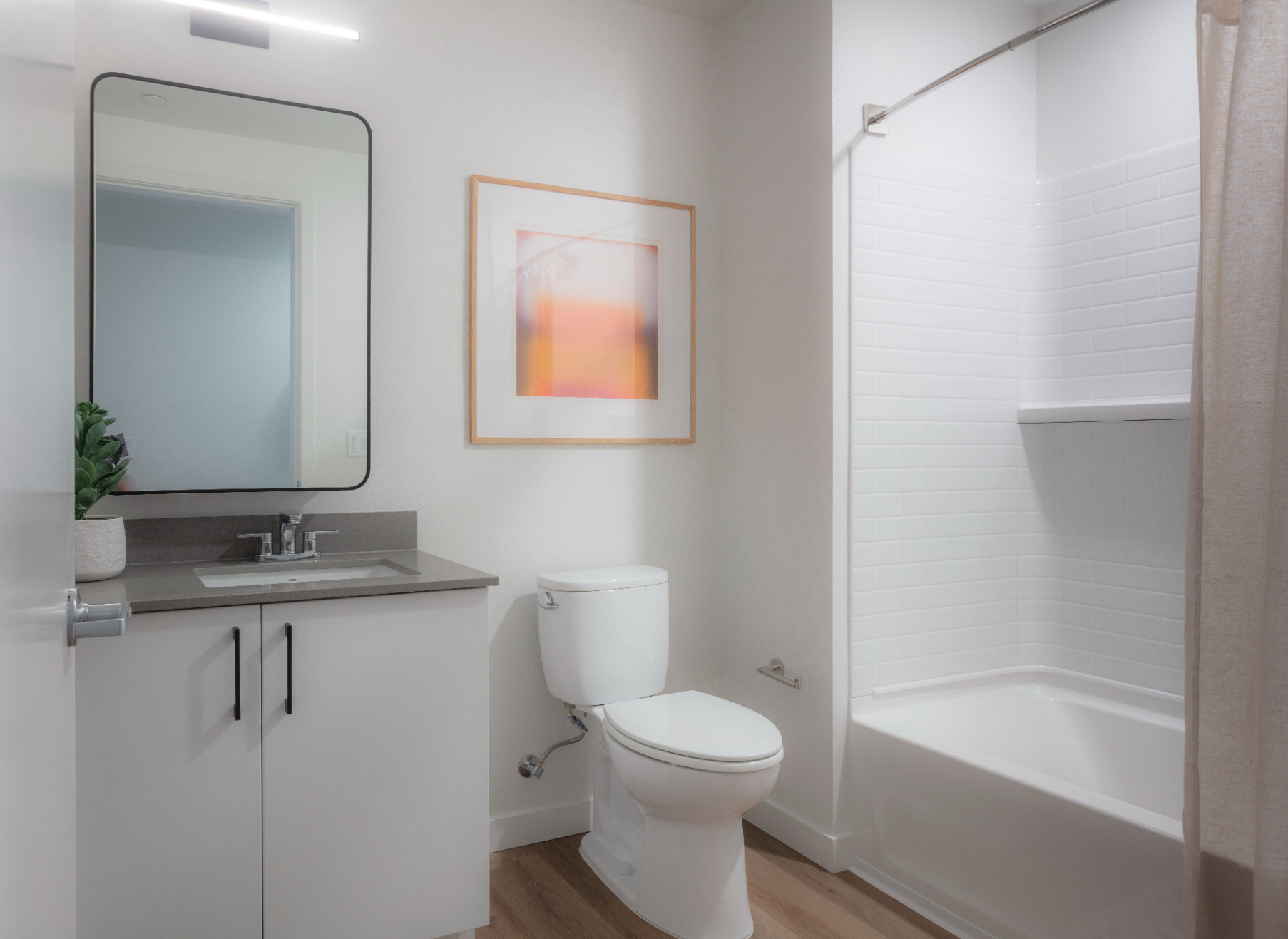 Apartment bathroom featuring a vanity, a framed mirror, and a white shower/tub with shower curtain
