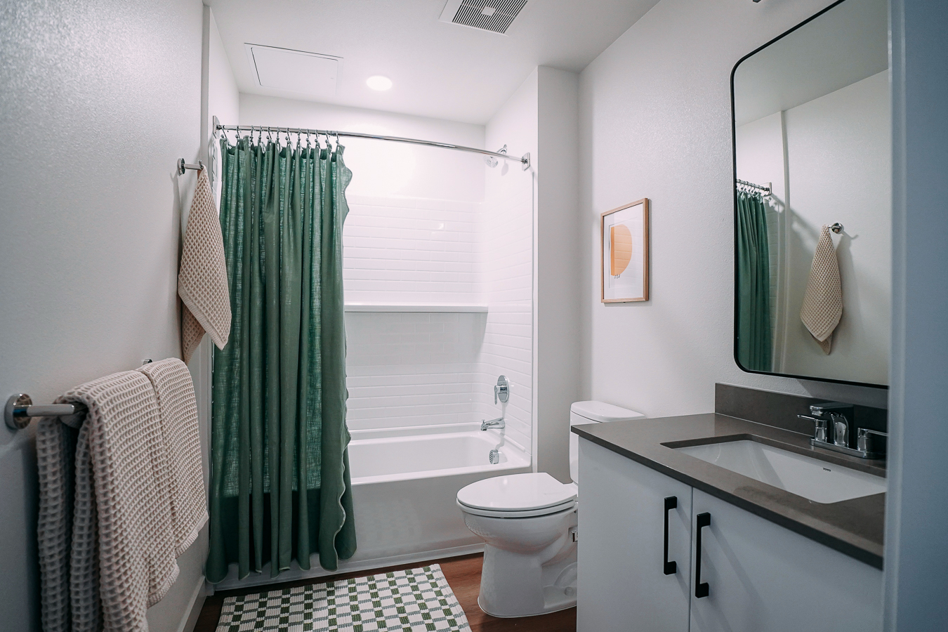 Apartment bathroom featuring a vanity, a framed mirror, and a white shower/tub with shower curtain