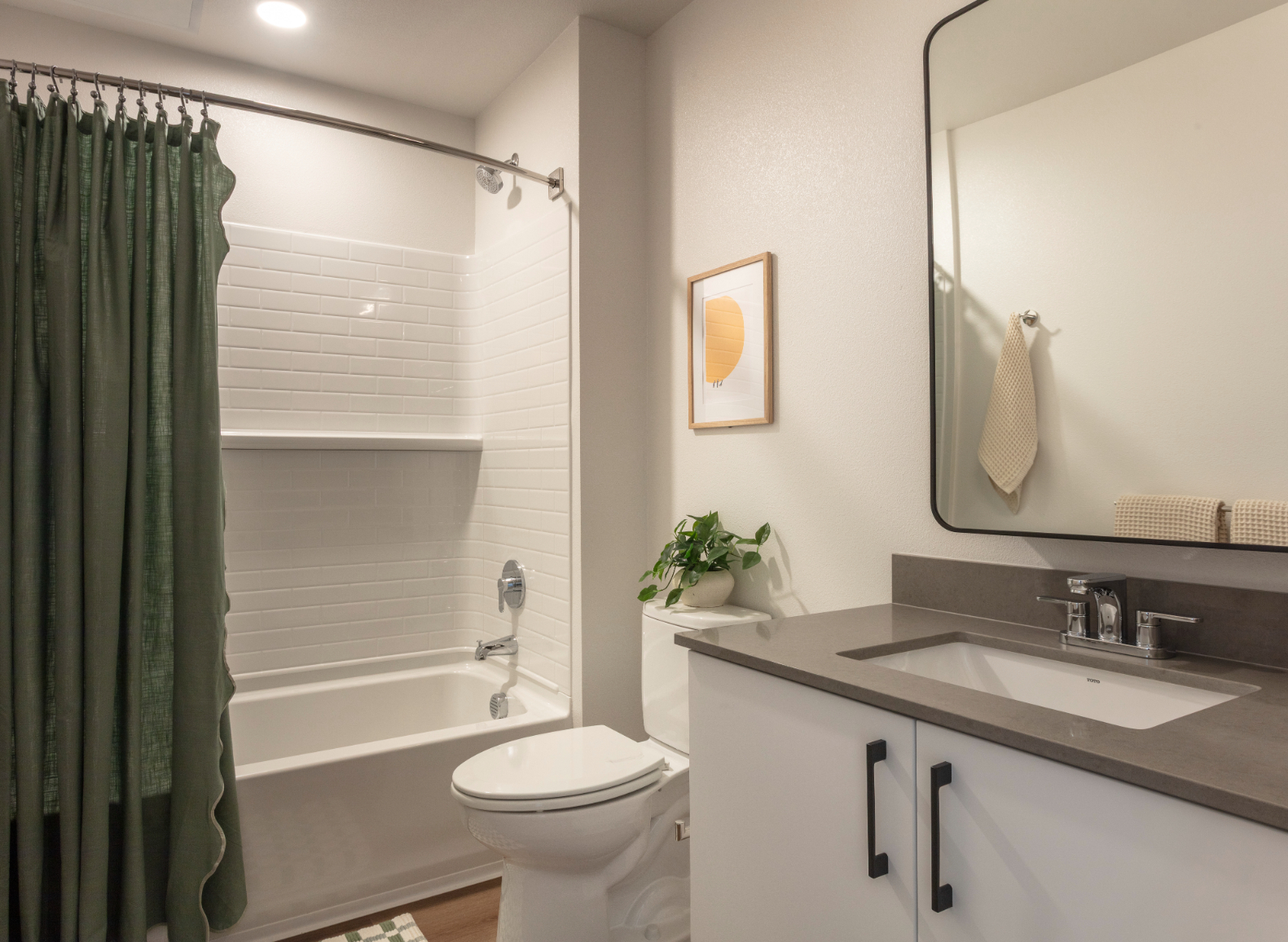 Apartment bathroom featuring a vanity, a framed mirror, and a white shower/tub with shower curtain
