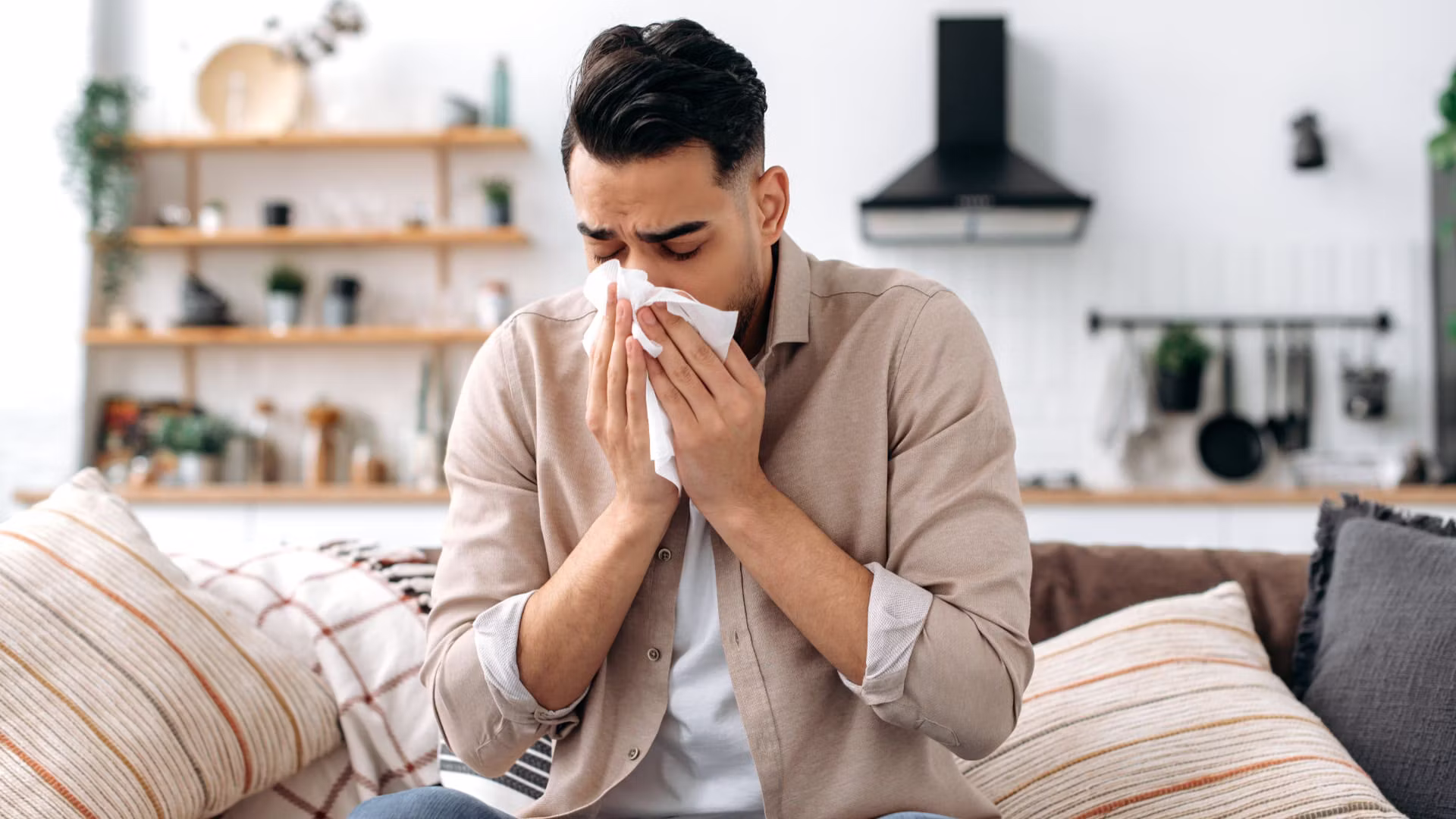 Man experiencing flu symptoms at home before seeking care from a primary care doctor in Lake Success, NY.