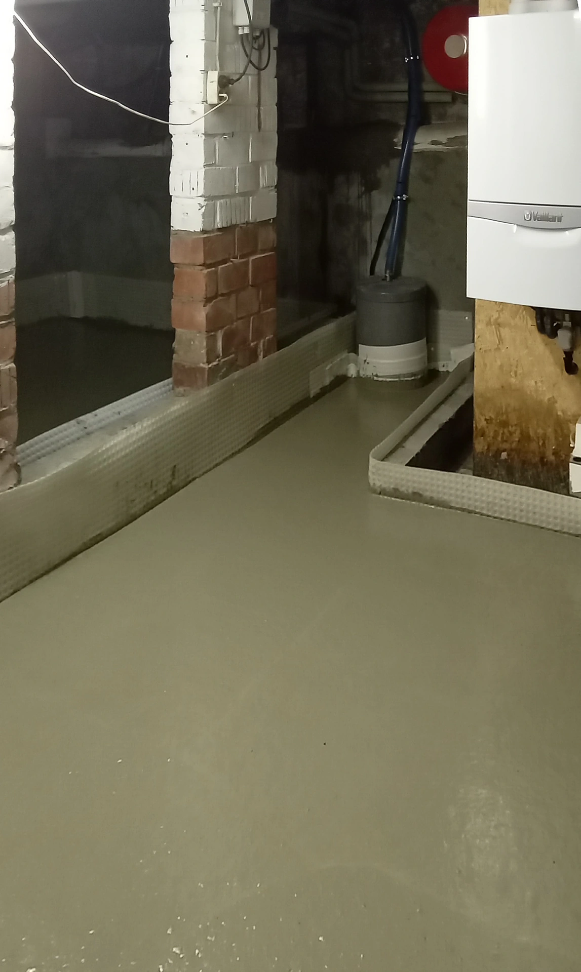 Eerste zone vers beton over de drainagematten bij de verwarmingsketel