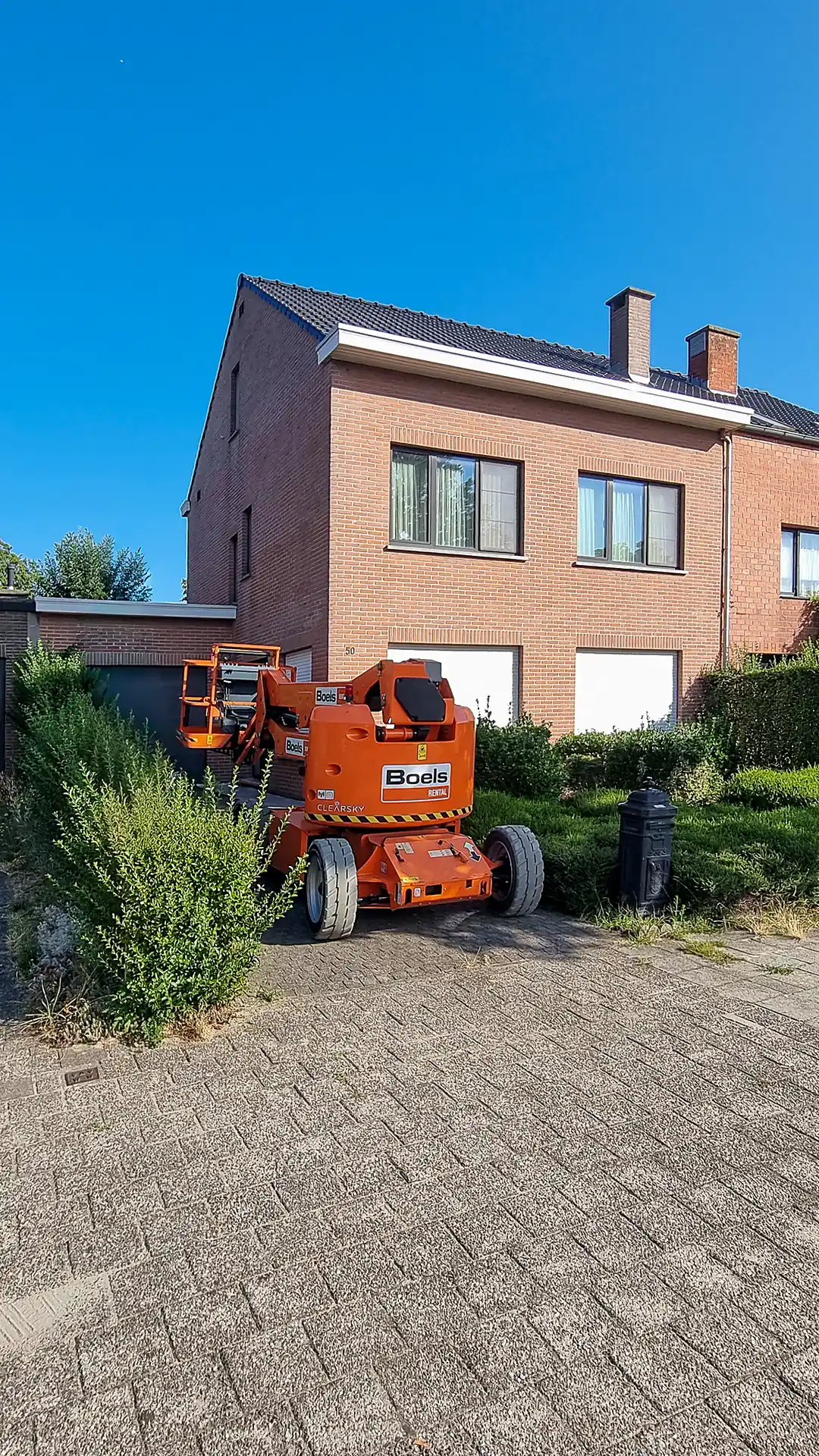 Hoogwerker opgesteld op de oprit voor de gevelwerken