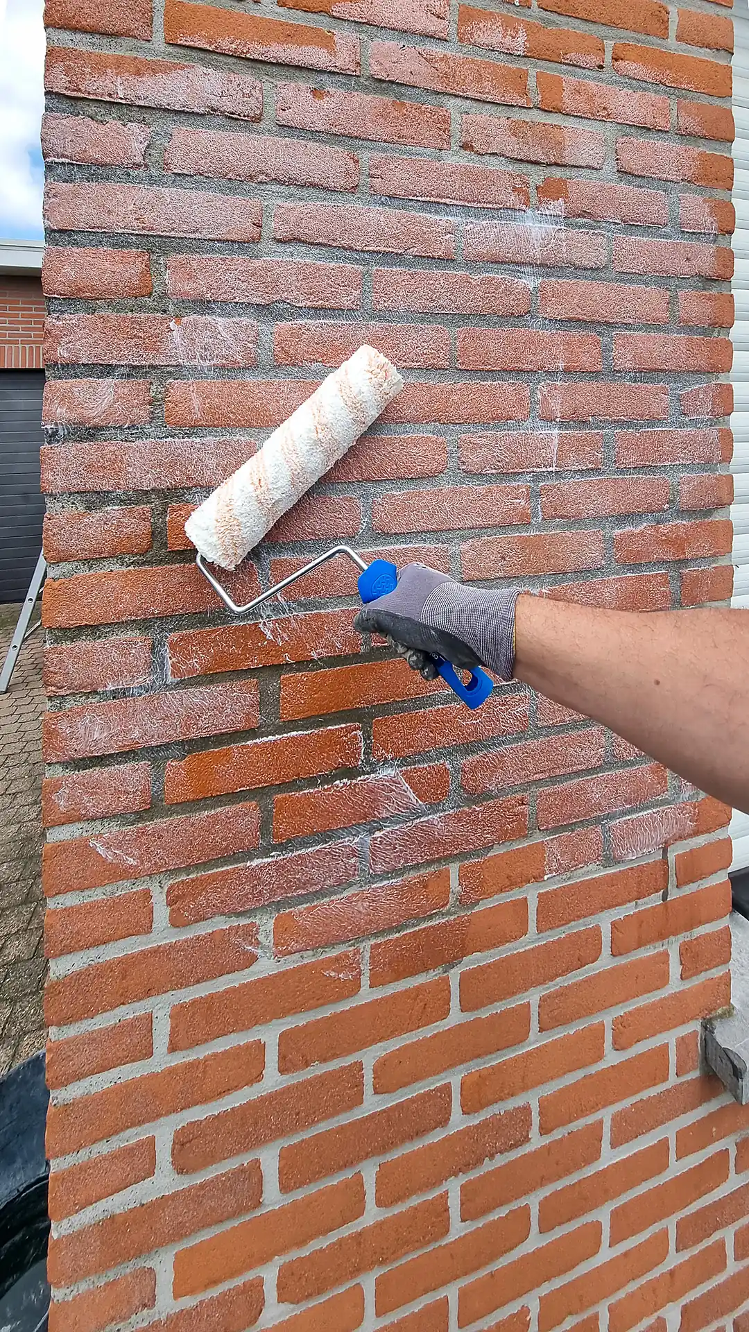 Roller met impregnatiemiddel op de bakstenen gevel