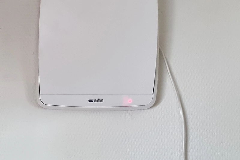 De witte ventilatie-unit op de badkamerwand