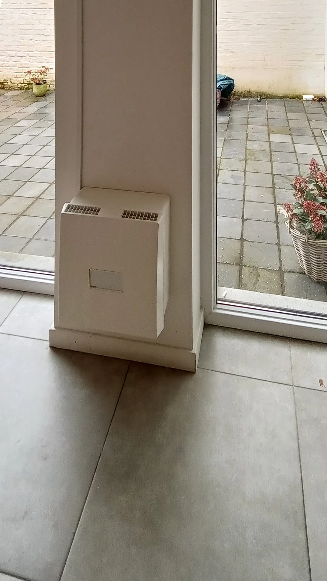 Decentrale ventilatie-unit afgewerkt aan de wand boven de tegelvloer