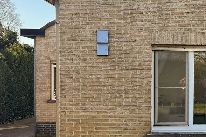 De ventilatiekap op de bakstenen gevelhoek boven de oprit