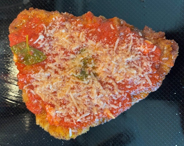 Burger with fried fries on black plate with sauce on the side