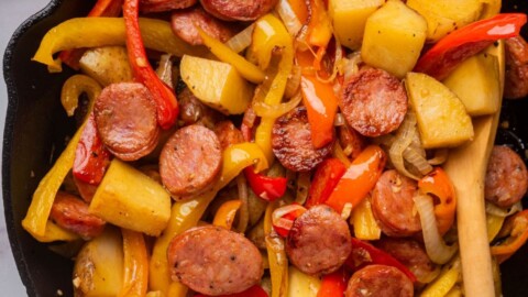 Burger with fried fries on black plate with sauce on the side