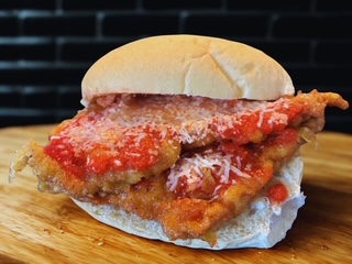 Positive young multiracial friends eating fast food and drinking beer in outdoor cafe