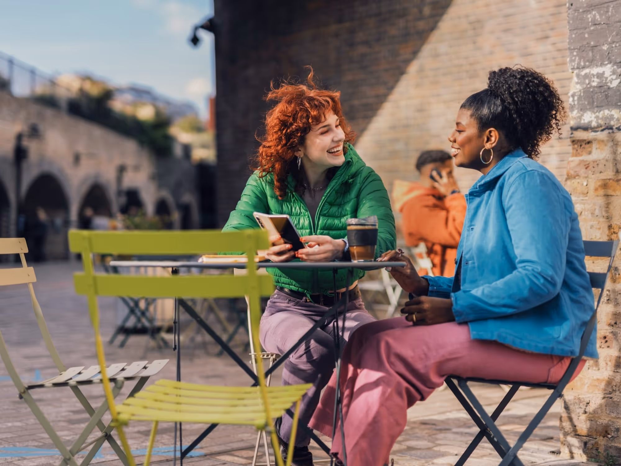 Two women enjoying coffee and conversation at an outdoor cafe table