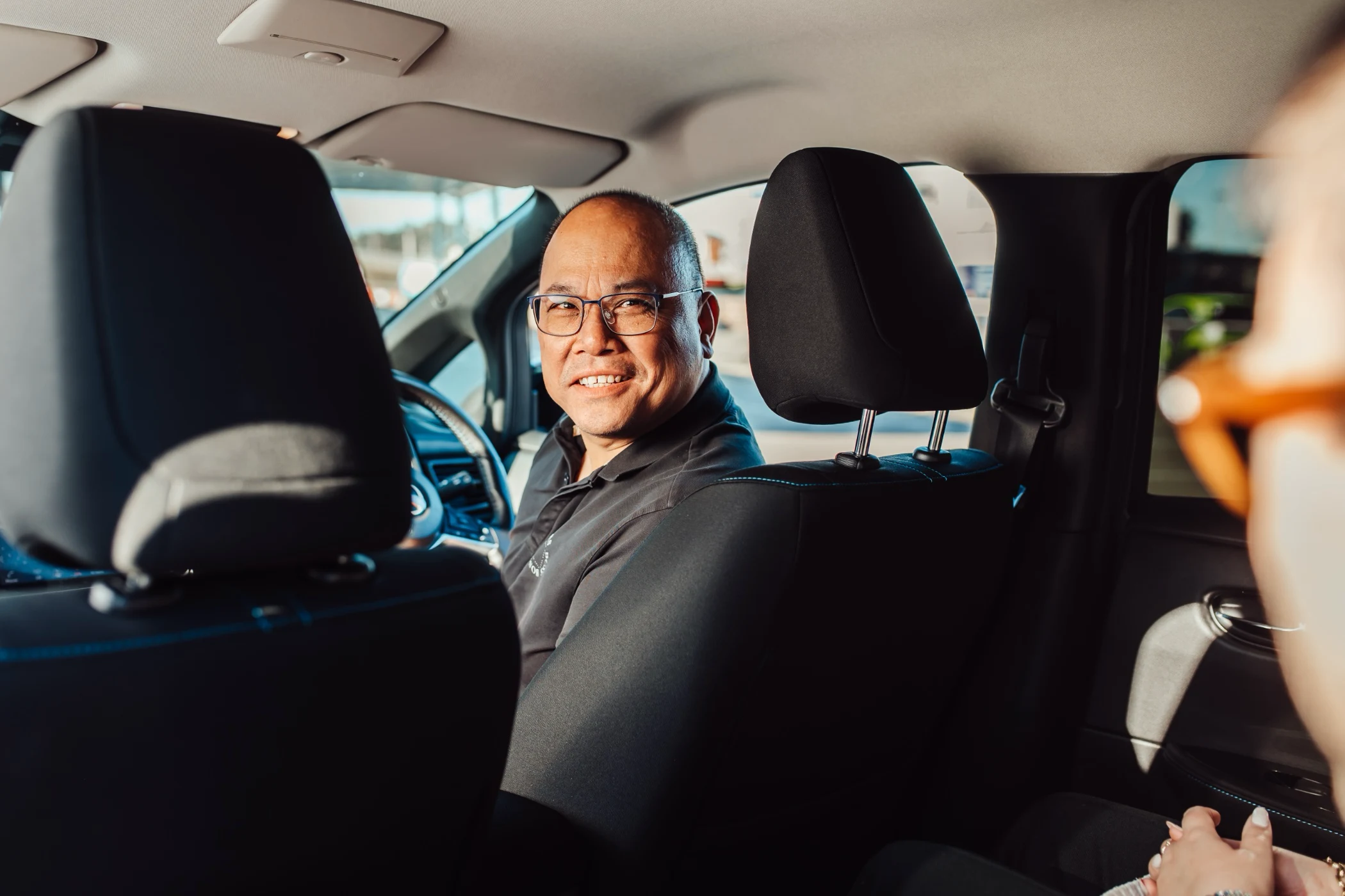Smiling person sitting in car, viewed from back seat