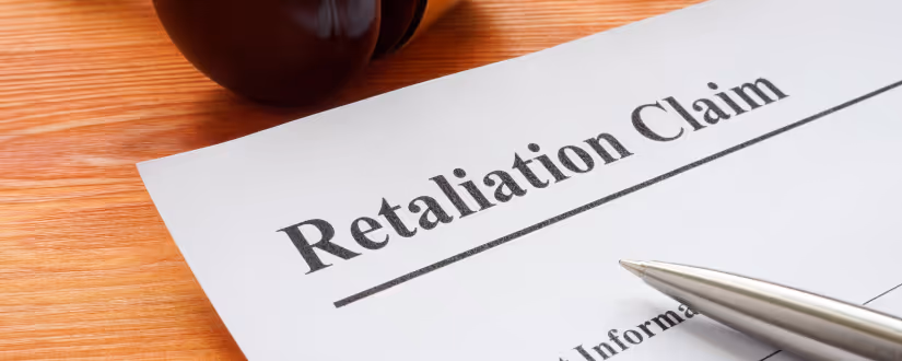 Close-up of a document titled 'Retaliation Claim' on a wooden desk with a pen and a gavel nearby.