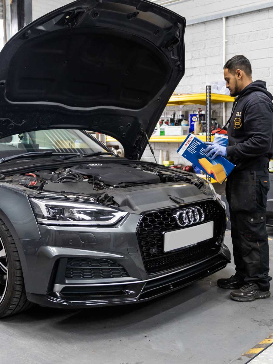 Technician working on a car engine in Bedford