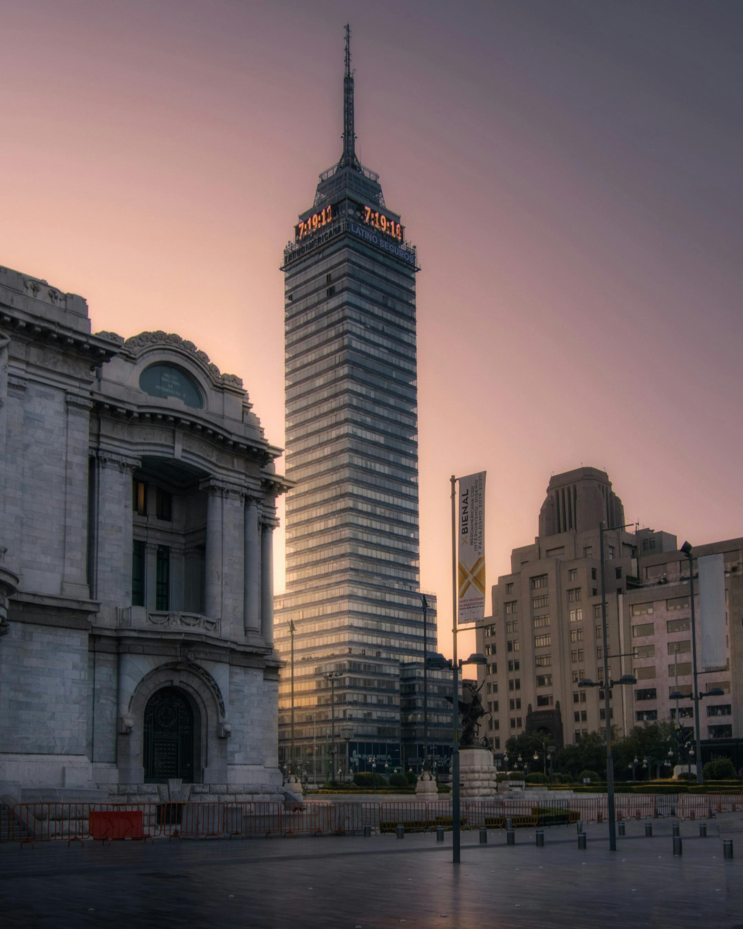 Tall Torre Latinoamericana skyscraper at sunset with historic buildings and a plaza in the foreground.