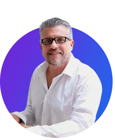 Middle-aged man with gray hair and glasses smiling, wearing a white shirt against a purple circular background.