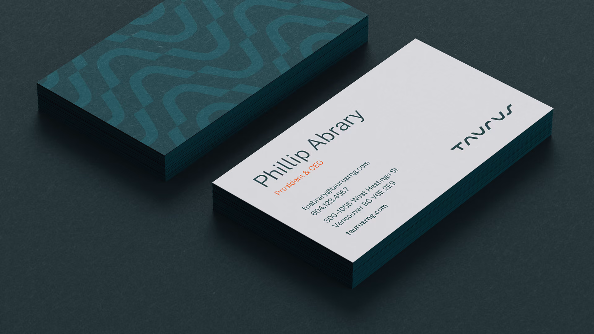 Stack of teal business cards with abstract wavy patterns next to a single white business card showing contact details for Phillip Albrary, President & CEO of Taurus Inc with email, phone, address in Vancouver, and company logo.