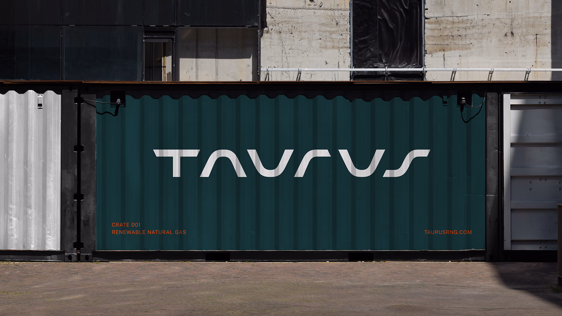 Dark green shipping container with the logo reading 'TAURUS' in large white letters centred, and smaller orange text reading CRATE 001, RENEWABLE NATURAL GAS, and TAURUSRNG.COM at the bottom corners.