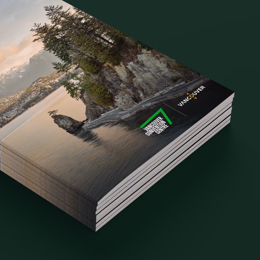 Stack of brochures featuring the Vancouver Convention Centre logo alongside the Destination Vancouver logo over an aerial view of a coastal rocky shoreline with trees and calm water.