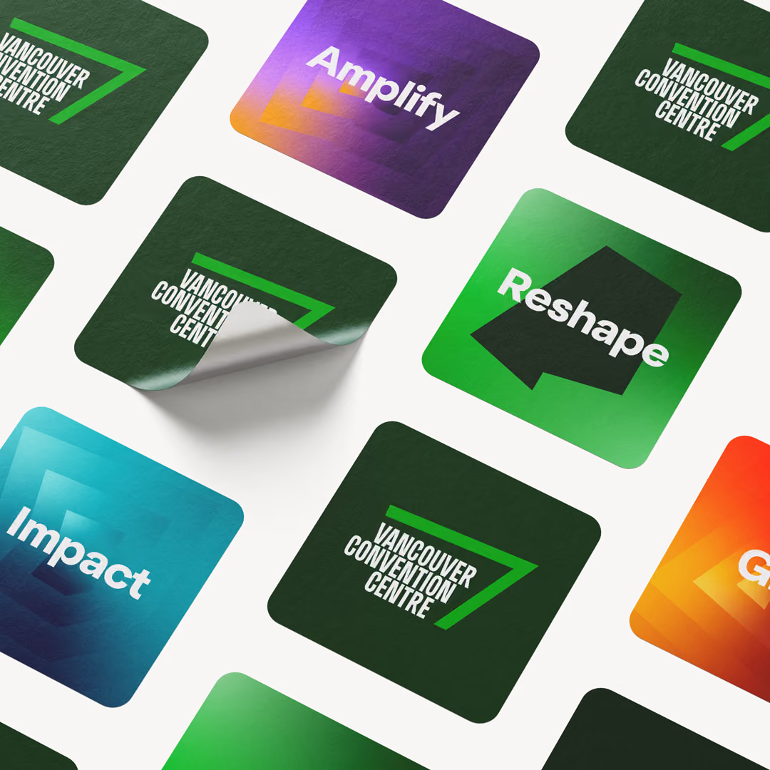 A collection of colorful square stickers with rounded corners arranged diagonally on a white background; some have the 'Vancouver Convention Centre' logo with a green angled line, and others have words like 'Amplify' on a purple radiating background, 'Reshape' on green with an abstract shape, and 'Impact' on blue.