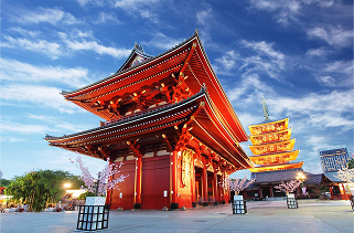 Traditional red Japanese temple and five-story pagoda under a partly cloudy sky at sunset.