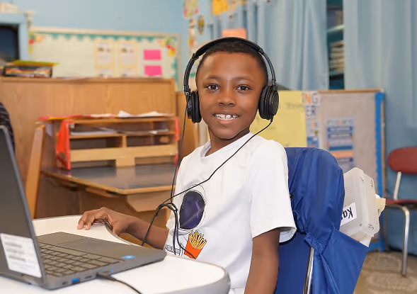 Student wearing headphones using laptop in classroom
