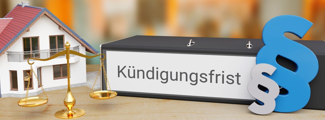 Miniature house with golden balance scale and binder labeled 'Kündigungsfrist' next to blue and white legal paragraph symbols.