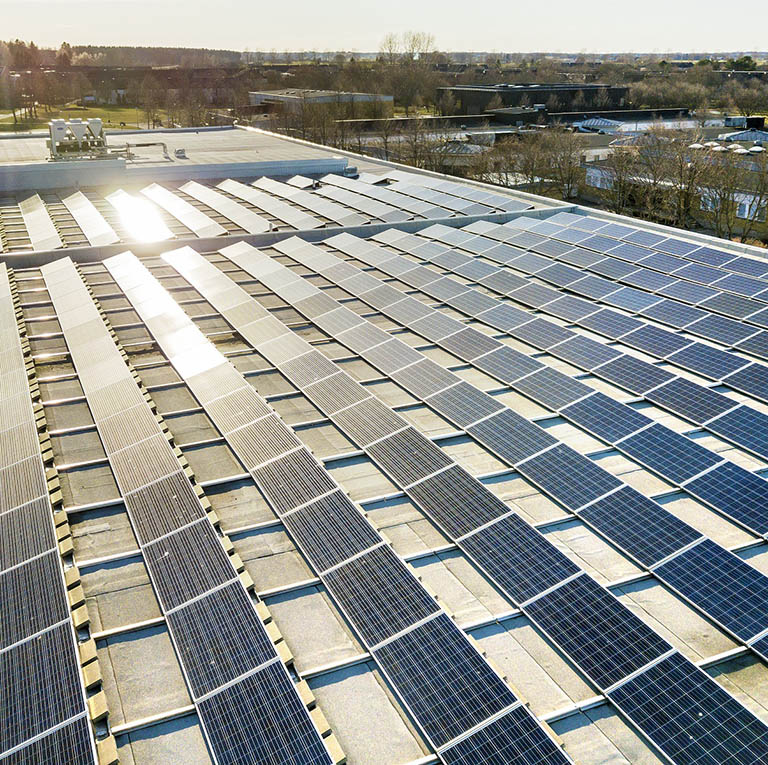 Luftaufnahme eines Industriedachs mit großer Solaranlage in ländlicher Umgebung