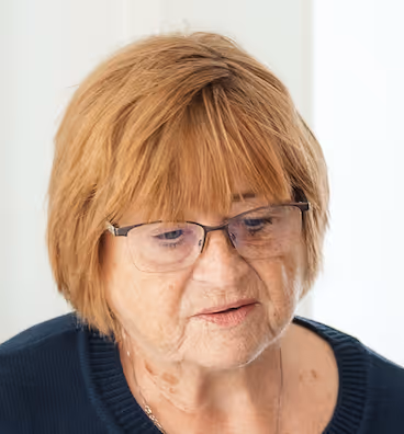 Freundliche ältere Kundenberaterin mit Brille und warmem Lächeln