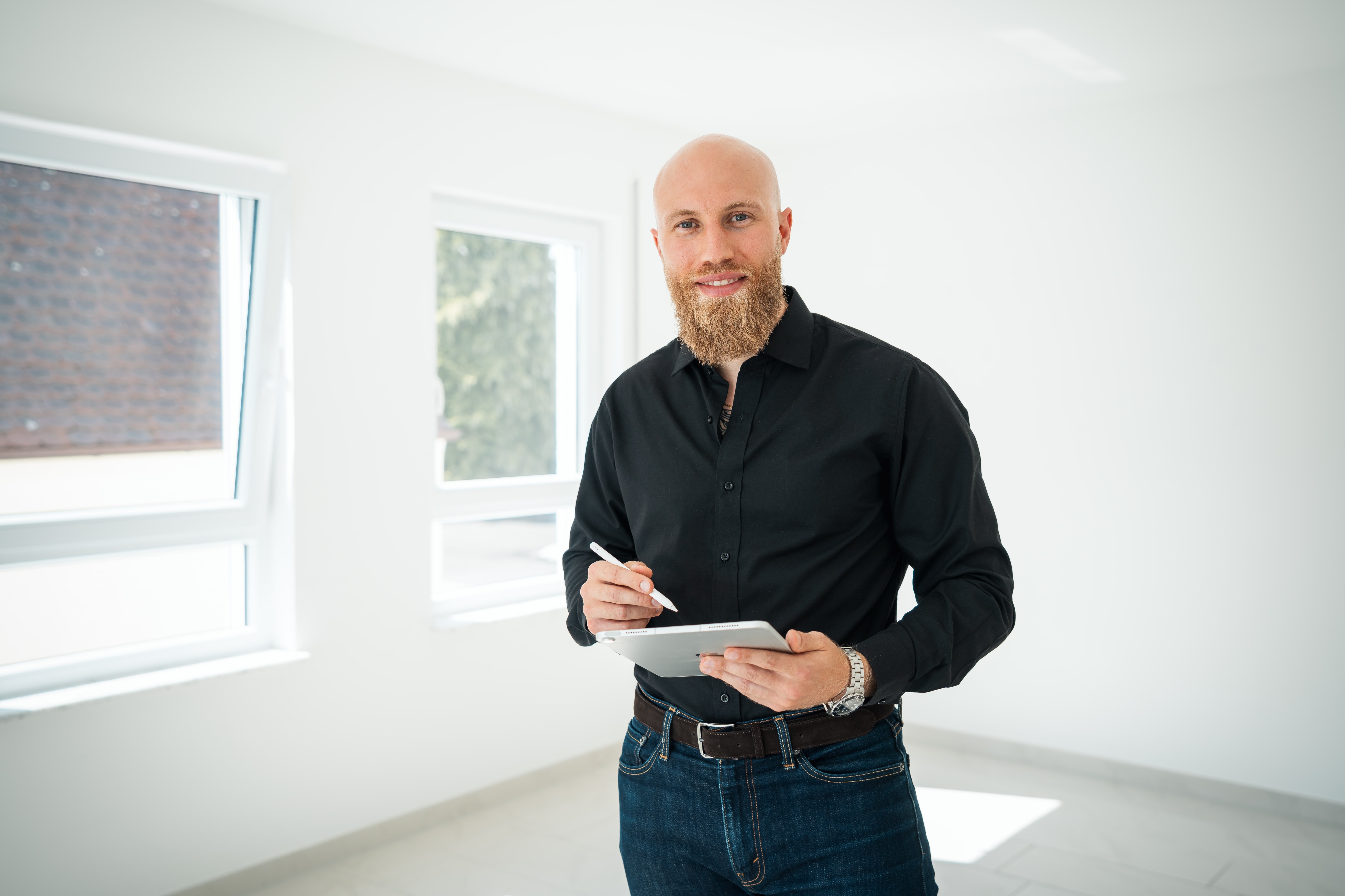 Professioneller Immobilienmakler mit Tablet in hellem Büroraum