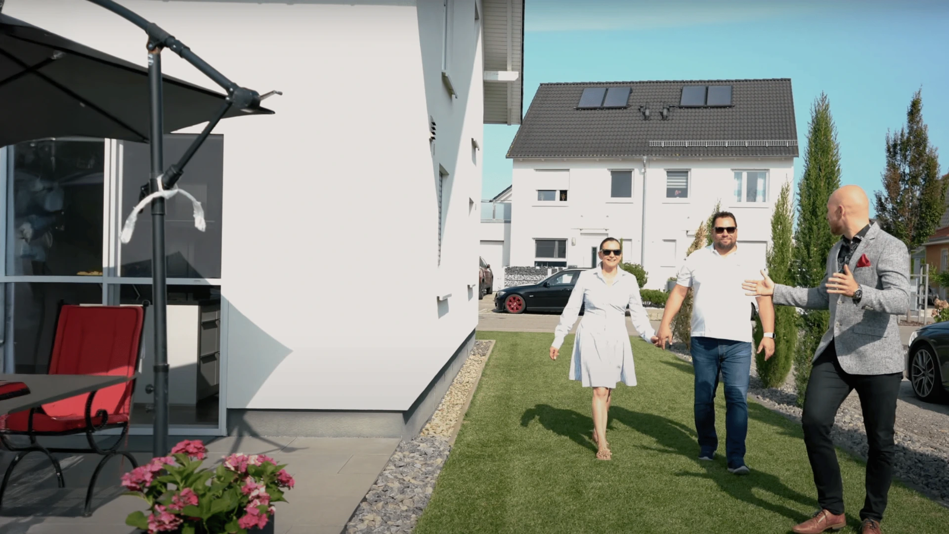 Immobilienmakler präsentiert modernes Einfamilienhaus mit Garten und Sonnenblenden