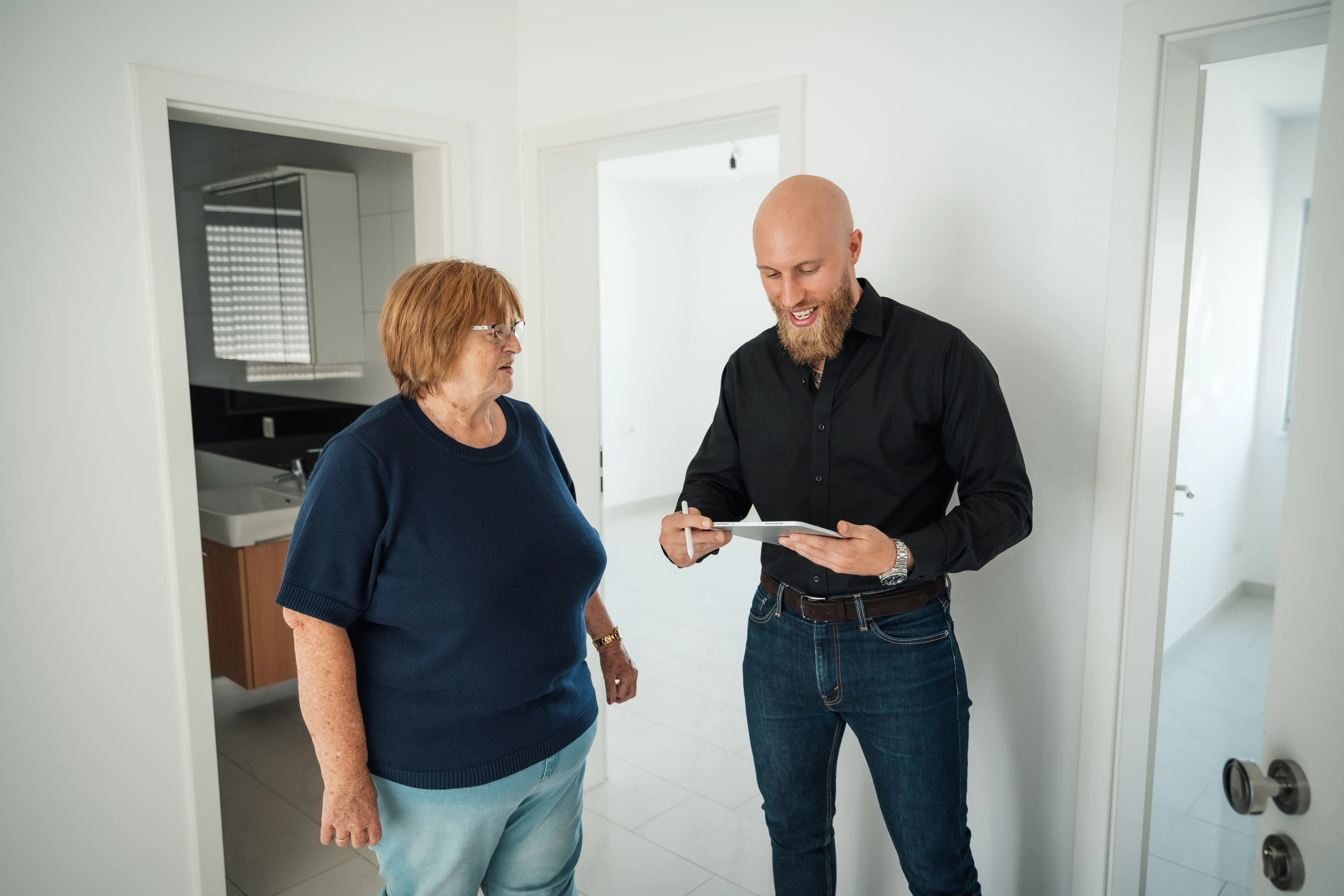 Immobilienmakler berät Kundin in moderner, weißer Wohnung